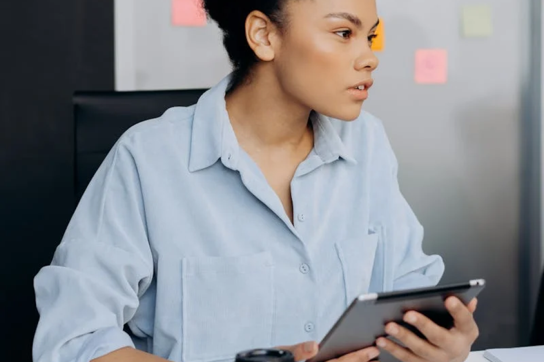 Professional woman holding a tablet, focusing on ISO 27001 certification, representing the importance of information security and compliance.