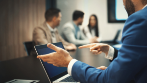 Photo of a businessman in a suit in a meeting working on a laptop 